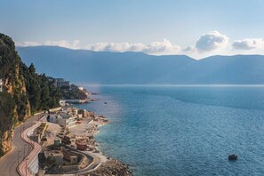 Une ville côtière avec une route sinueuse, des bâtiments et une vue sur la mer et les montagnes.