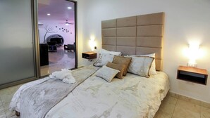 Ett hotellrum med en stor säng, en sänggavel, sängbord och utsikt över den inre delen av byggnaden.