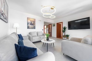 A modern living room with a sofa, a coffee table, a TV, and a painting on the wall. - Villa Nick-sunset Premium Apartment (Konavle)