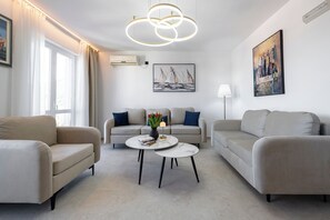 A modern living room with a sofa set, two coffee tables, a painting, and a ceiling light fixture. - Villa Nick-sunset Premium Apartment (Konavle)