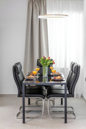 A dining area with a table, chairs, and a vase of flowers. - Villa Nick-sunset Premium Apartment (Konavle)