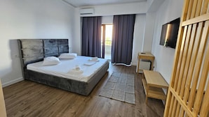 Una habitación de hotel con cama, televisión, separador de madera y equipo de aire acondicionado.