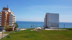 Un edificio frente al mar, con vistas al océano, un espacio con césped y una obra en construcción.