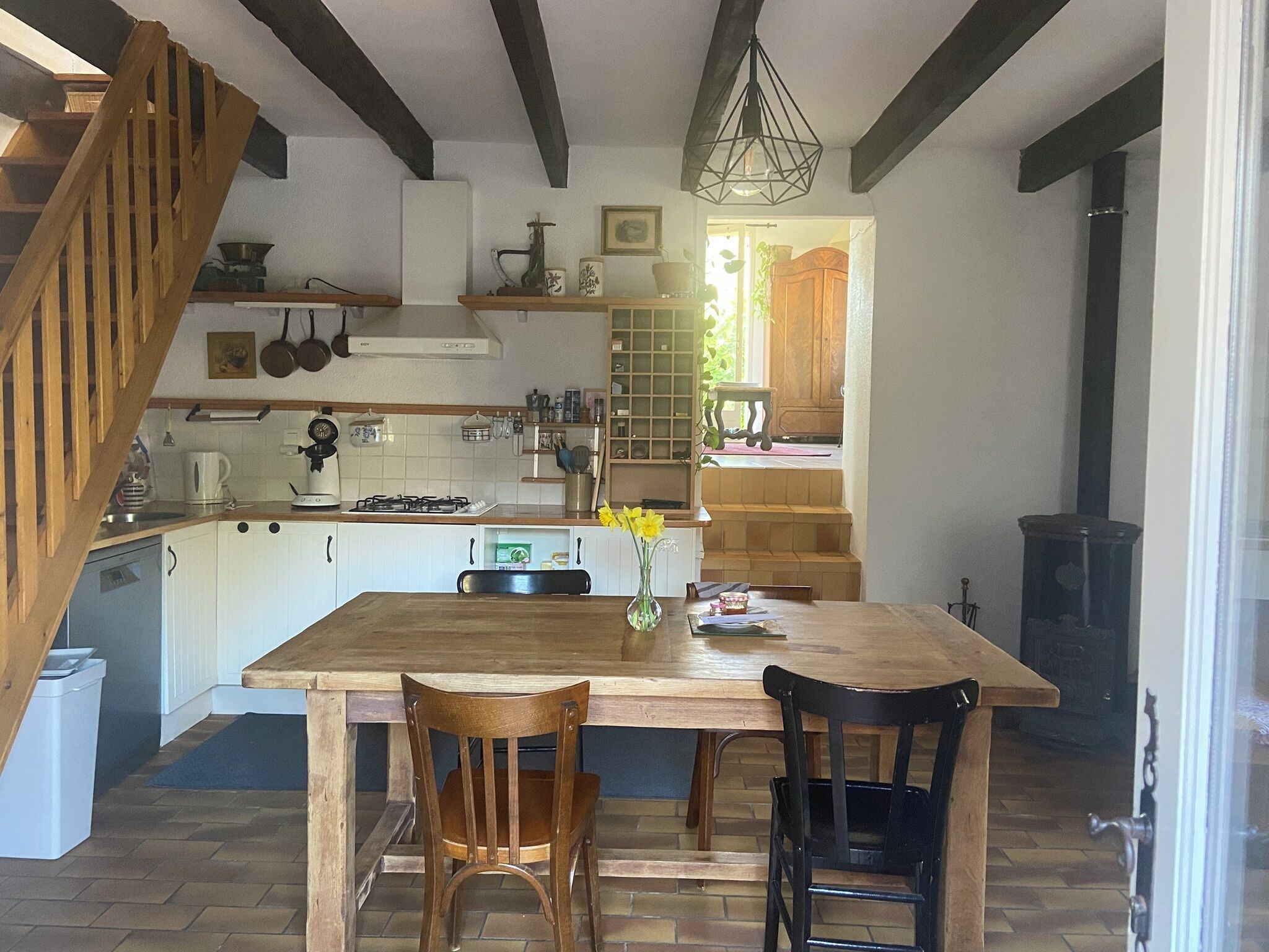 Een keuken met een houten tafel, twee stoelen, een fornuis en een hangende lamp.