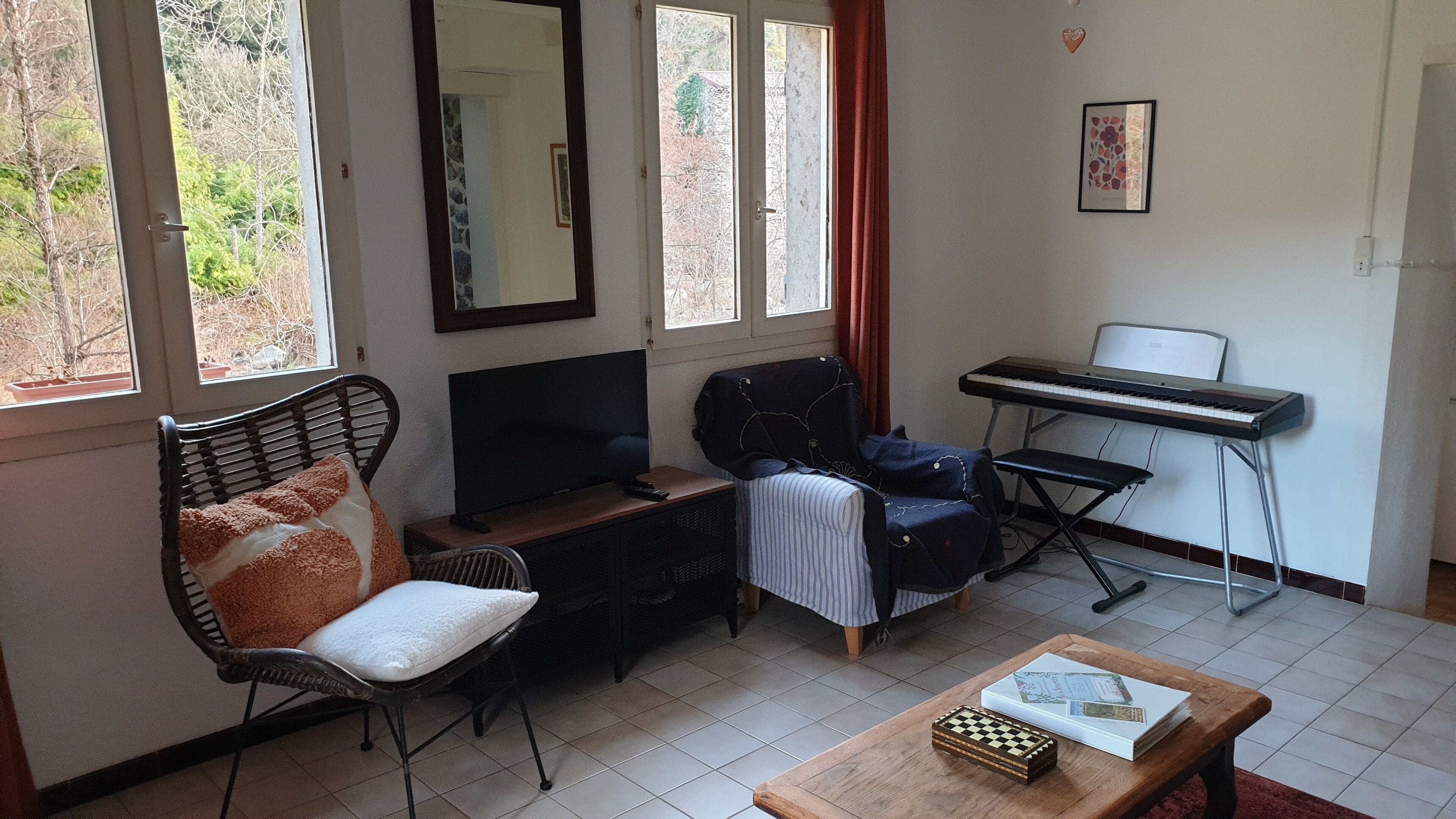 A living room with a sofa, a television, a piano, and a chessboard.