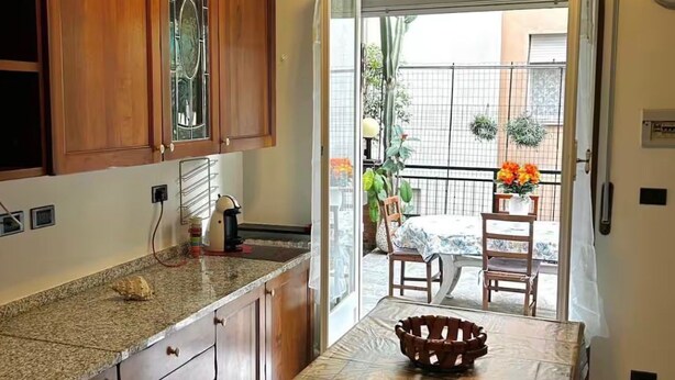 A kitchen with wooden cabinets, a granite countertop, and a dining table with a patterned tablecloth.