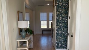 Ein Flur mit Holzdielen, einer weißen Tür und einer Wand mit Blumenmuster-Tapete.