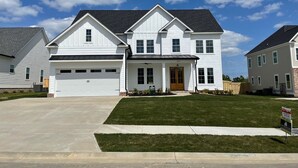 Ein zweigeschossiges Haus mit Garage, Veranda und einem gepflegten Rasen.