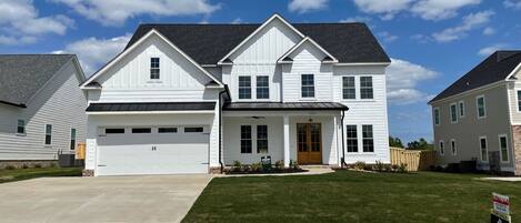 A two-story house with a garage, a front porch, and a well-maintained lawn.