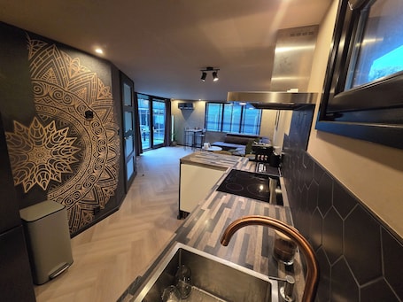 A modern kitchen with a patterned wall, a large window, and a stainless steel range hood.