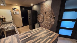 A modern kitchen with a herringbone-patterned countertop, a black refrigerator, and a decorative wall piece. - Exclusive wellness bungalow, 6 person Jacuzzi! Woodland Wellness Resort (Ermelo)