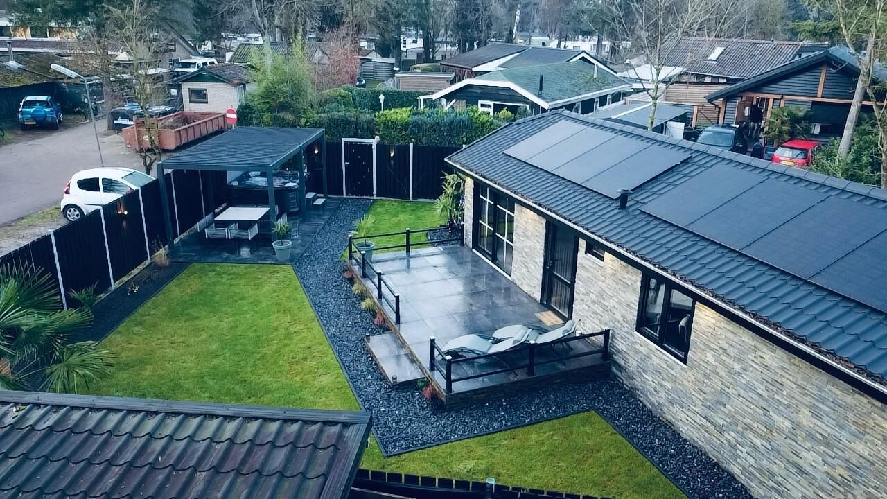 Een woonhuis met een overdekte patio, een gazon en een stenen gebouw.