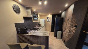 A modern kitchen with a built-in stove, a coffee machine, and two bar stools. - Exclusive wellness bungalow, 6 person Jacuzzi! Woodland Wellness Resort (Ermelo)