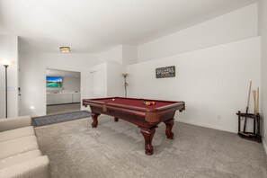 A pool table in a room with a carpeted floor, a sofa, a billiards sign, and a lamp. - A newly renovated mountain basecamp with two king suites, perfect for families exploring American Fork Canyon. (American Fork)