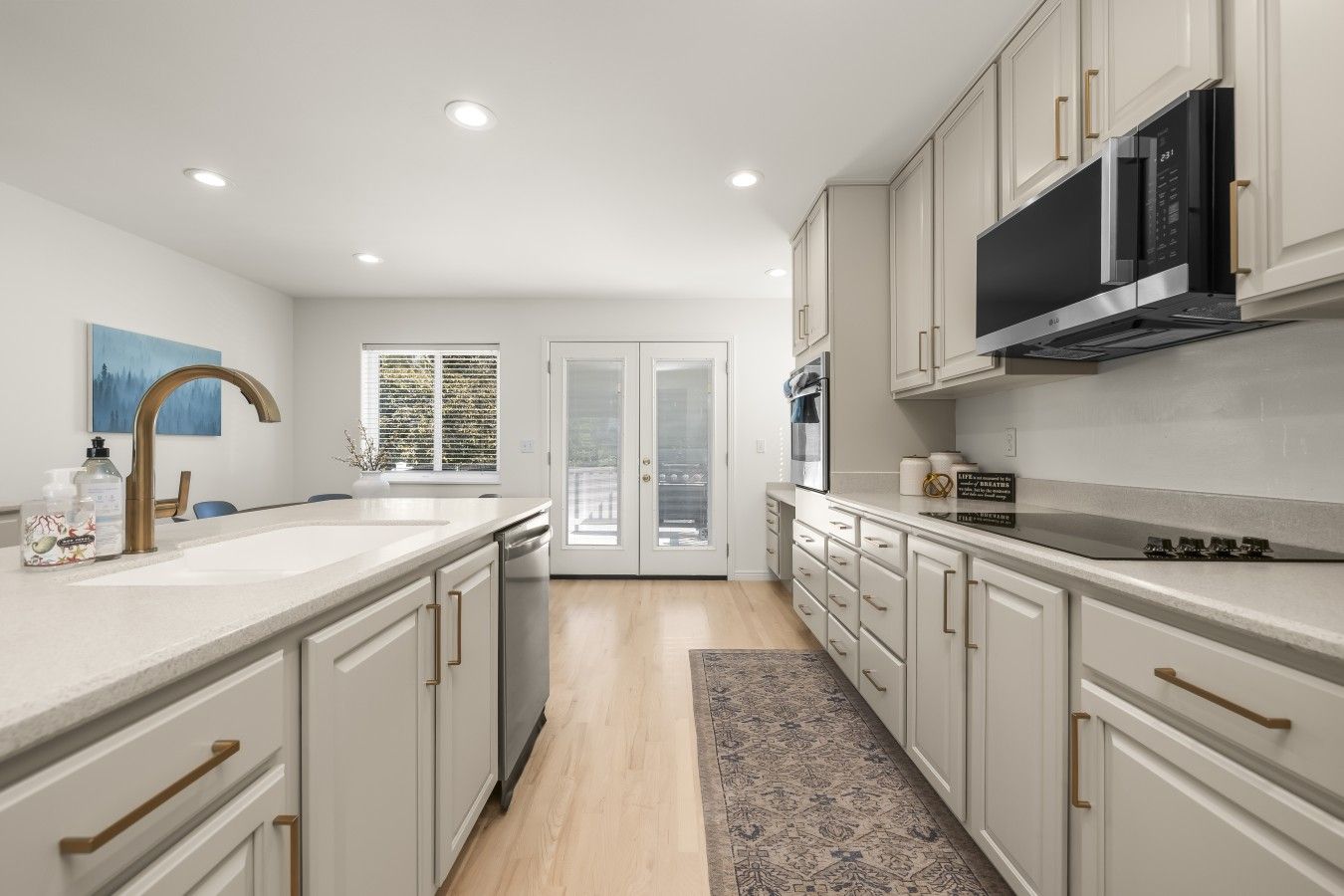 A modern kitchen with white cabinetry, stainless steel appliances, and a large island with a sink.