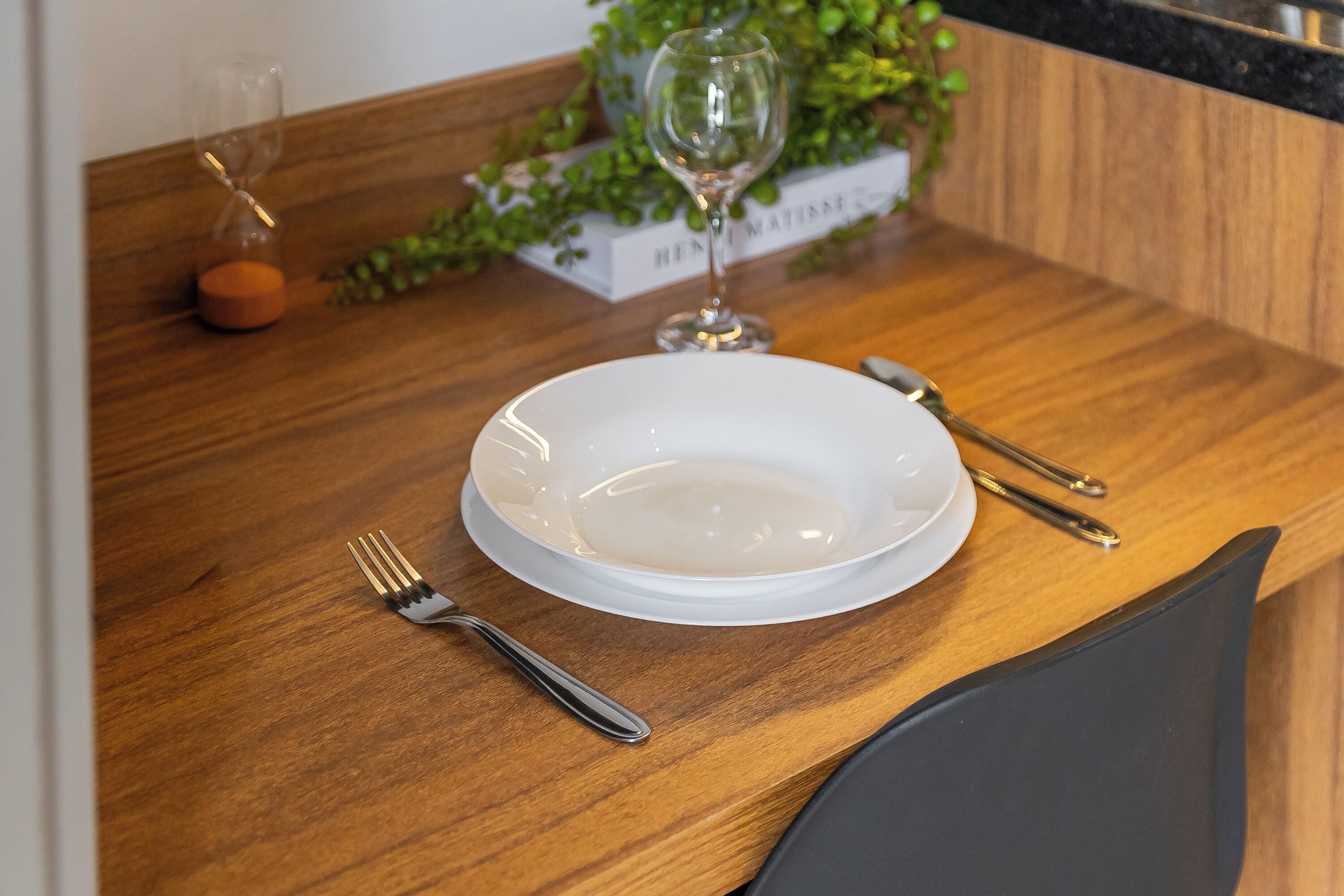 Une table à manger avec une assiette blanche, une fourchette, un couteau et un verre à vin.