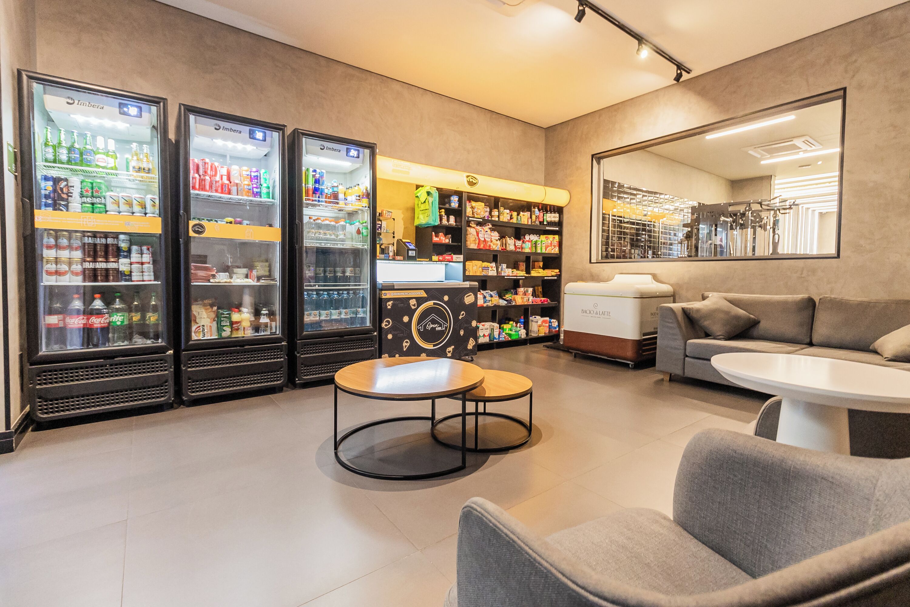 A modern interior with vending machines, a sofa, a round table, and a large mirror.