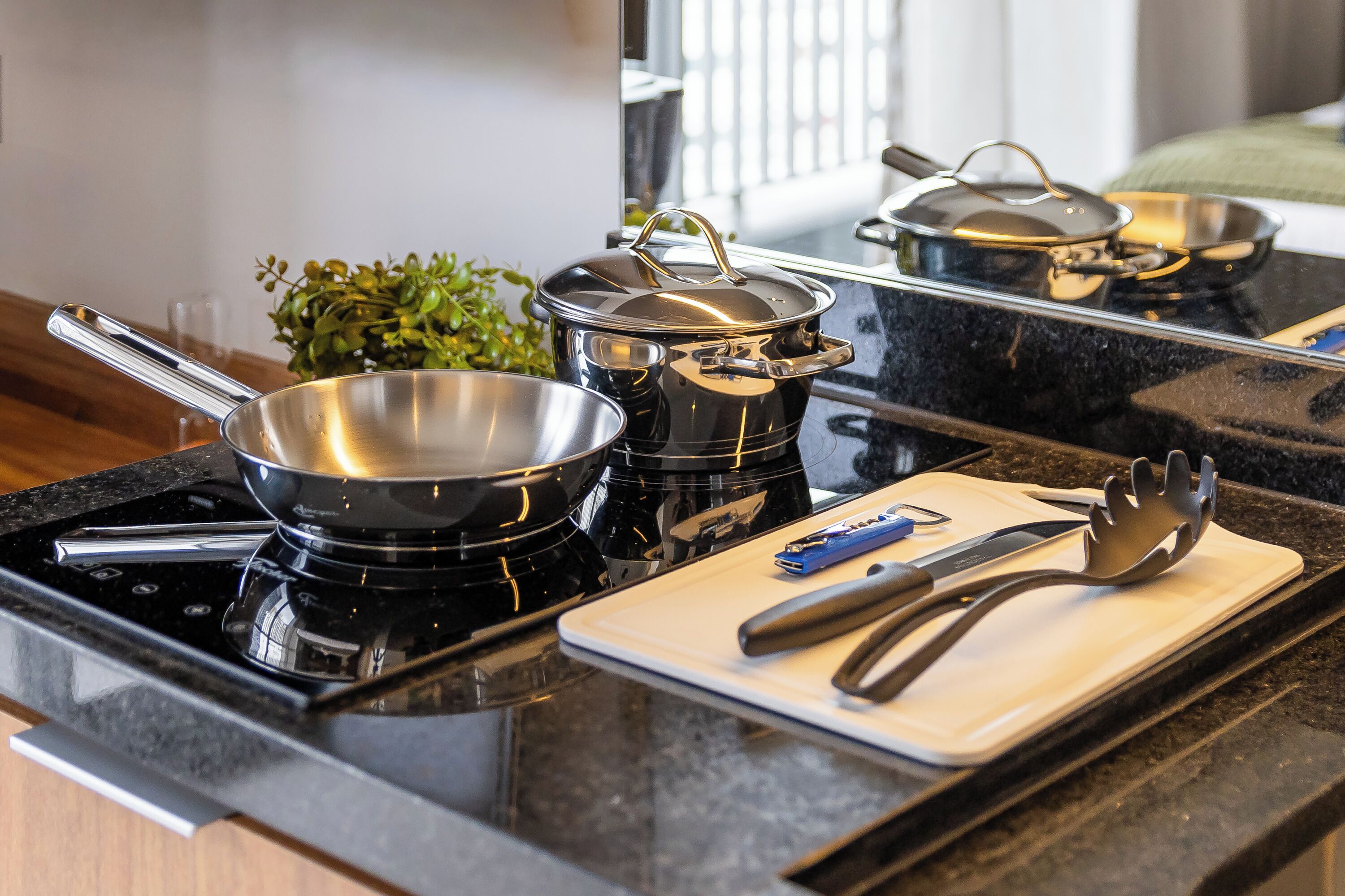 A kitchen with a stove, pots, a cutting board, and utensils.