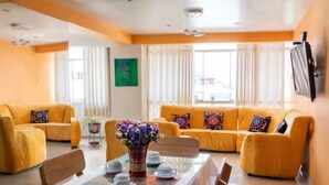 A living room with a glass-top dining table, two sofas, and a TV mounted on the wall. - Apartment close to the main square + airport pickup (cusco)