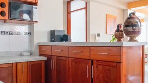 A kitchen with wooden cabinets, a microwave, and a coffee maker. - Apartment close to the main square + airport pickup (cusco)