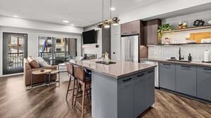 A modern kitchen with a central island, grey cabinets, and a built-in TV. - 3 Bed/3 Bath Cozy Mountain Retreat (Canmore)