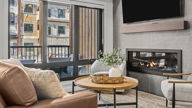 A living room with a sofa, a coffee table, a fireplace, and a large window. - 3 Bed/3 Bath Cozy Mountain Retreat (Canmore)