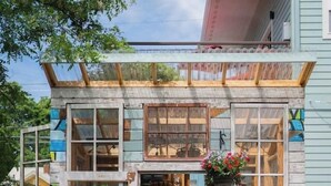 Eine rustikale Holzhütte mit großen Fenstern, einer Veranda und einem hängenden Blumentopf.