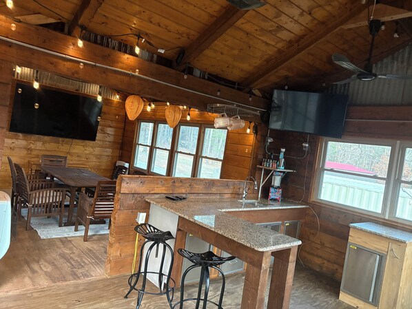 Ein Holzblockhaus-Interieur mit Barbereich, Holzmöbeln und einem an der Wand befestigten Fernseher.