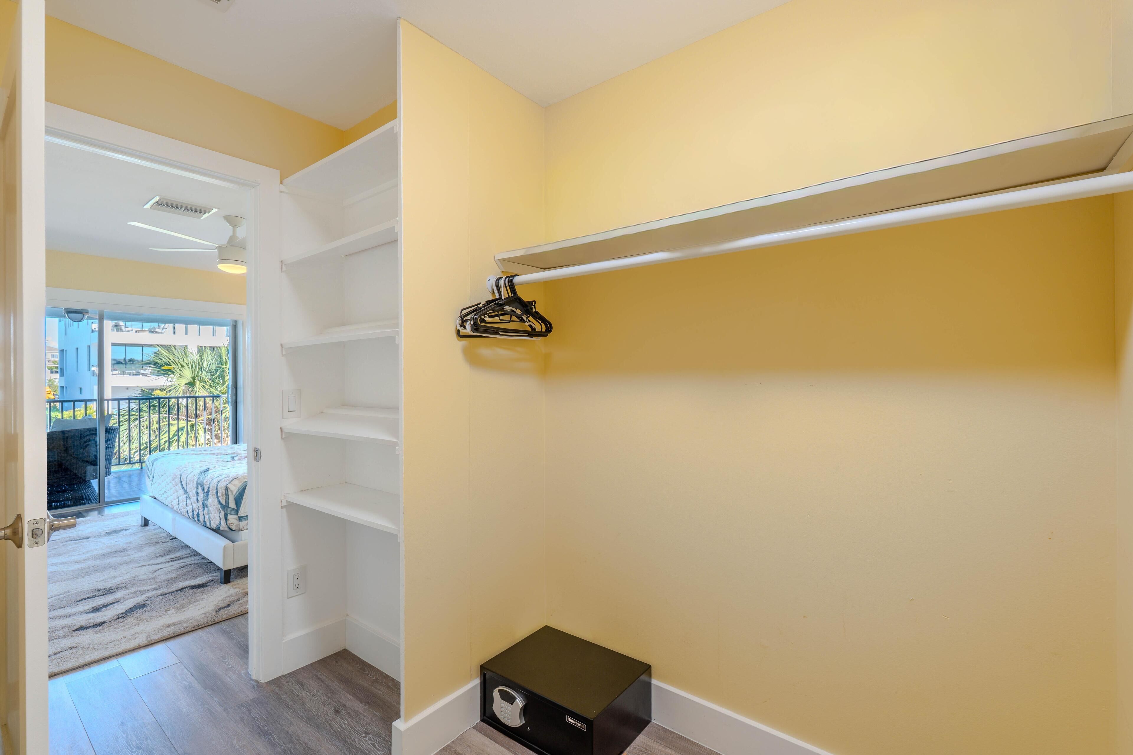Une pièce comprenant un lit, une armoire blanche avec des étagères, une petite boîte noire et un balcon doté d’une balustrade.