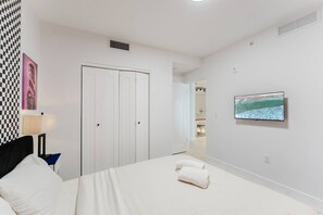 Une chambre d’hôtel avec un lit, une télévision, une porte et un tableau accroché au mur.