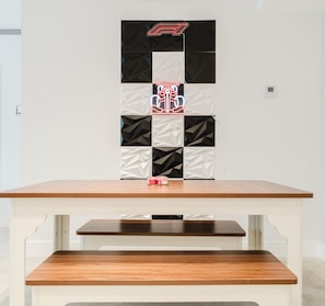 Een tafel met een bankje voor een muur met een geometrisch patroon en een neonbord.