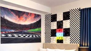 A bedroom with a checkered floor, a bed with a racing car-themed bedspread, a wall with a racing track mural, and a checkered wall decoration. - Luxe F1 3BR | Steps to Design District & Wynwood (Miami)