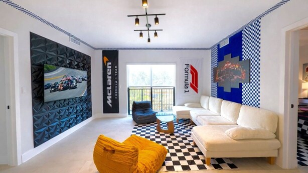 A modern living room with a checkered floor, a sofa, a yellow chair, and a TV mounted on a geometric-patterned wall. - Luxe F1 3BR | Steps to Design District & Wynwood (Miami)