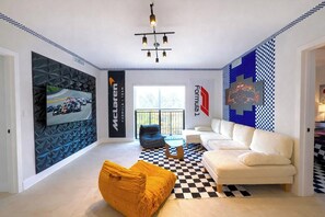A modern living room with a large TV, a sofa, a patterned rug, and a checkered floor. - F1 Getaway NEW Build Luxury Stay w/ FREE Parking (Miami)