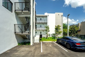 Een meerlaags woongebouw met een parkeerplaats en een blauwe auto op de parkeerplaats.