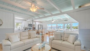 A spacious living area with two sofas, a round coffee table, and a kitchen in the background. - Palmetto Breeze (Fort Myers Beach)