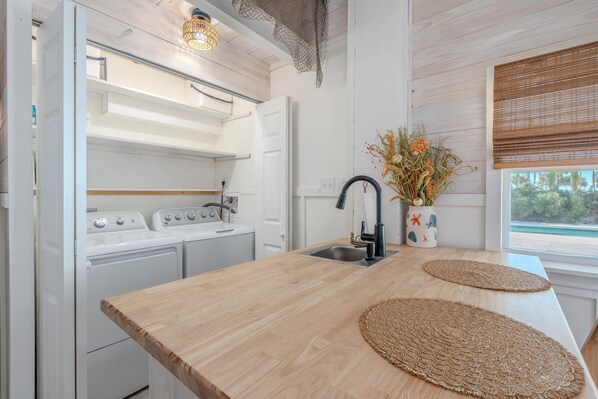 A kitchen with a wooden countertop, a sink, and a window with a view. - Palmetto Breeze (Fort Myers Beach)