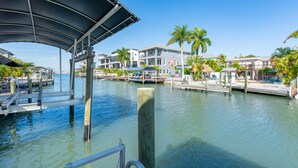 A waterfront property with a covered dock, a marina, and residential buildings with balconies. - 218 Dolphin Beach House (Fort Myers Beach)
