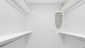 Ein schmales Zimmer mit weißen Wänden, einer Duschkabine, einem Handtuchhalter und einer kleinen Ablagefläche.