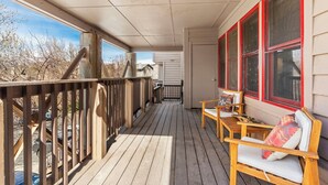 A wooden deck with a railing, a bench, and a table with cushions.