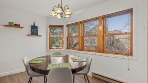 A dining area with a round table, chairs, and a chandelier.