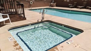 A rectangular pool with a tiled edge, a metal ladder, and lounge chairs in the background.