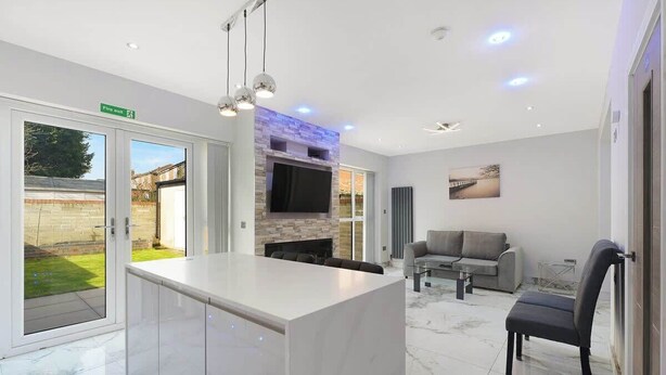 Un interior moderno con una isla de cocina, zona de estar y chimenea.