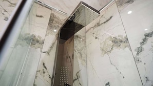 Un baño moderno con paredes de mármol y zona de ducha.