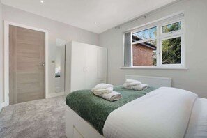 A bedroom with a bed, a wardrobe, a window, and a door. - Stylish Home with Parking and Easy City Access (Crumpsall)