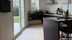 Una cocina moderna con una isla grande, un ventanal y un televisor de pantalla plana.