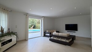 Amplia sala de estar con una televisión de pantalla plana, un sofá y un comedor con mesa.
