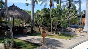 Un complexe hôtelier tropical doté d’une structure à toit de chaume, de palmiers et d’un sentier en pierre.