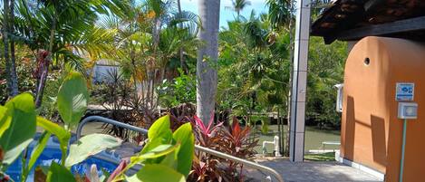 A pool area with a water slide, surrounded by tropical plants and a small building with a sign.