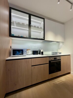 Eine moderne Küche mit Holzausstattung, einer Mikrowelle, einem Wasserkocher und einem Toaster.